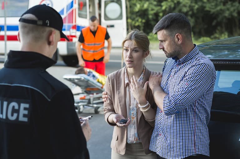 A couple speaking to a paramedic after an auto accident